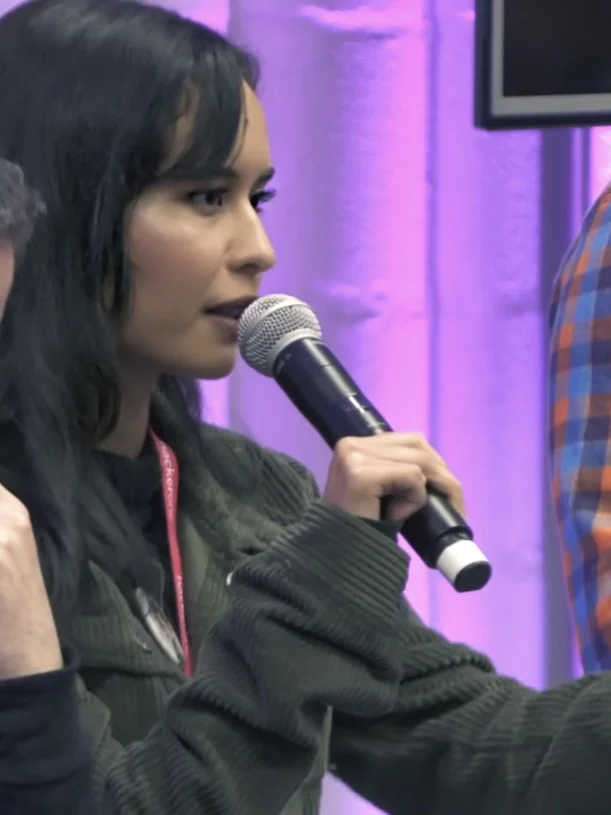 Nemesis Contreras speaking into a microphone on a panel at a Google Play event.